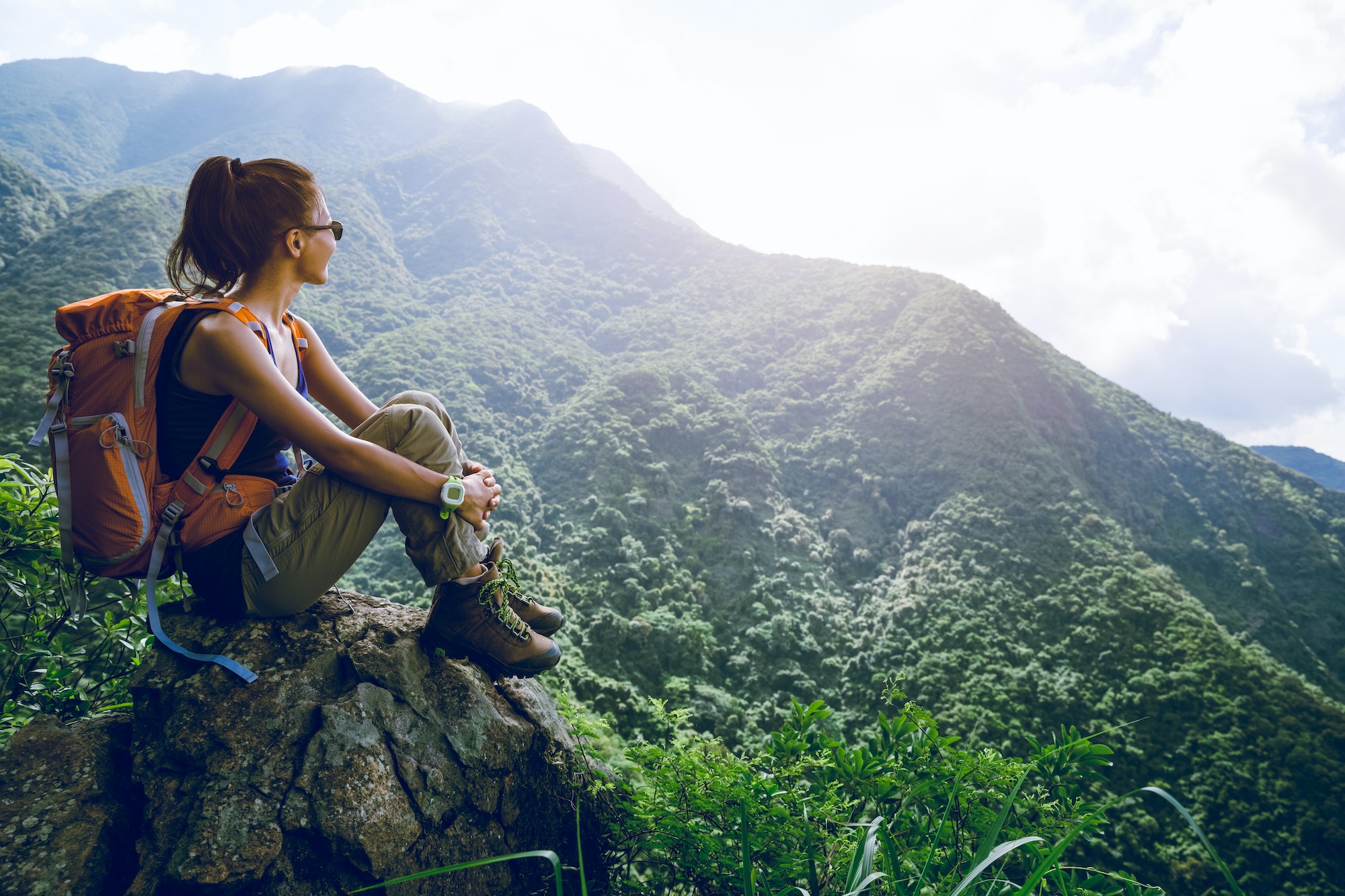 Woman hiker sit on mountain top enjoy the view